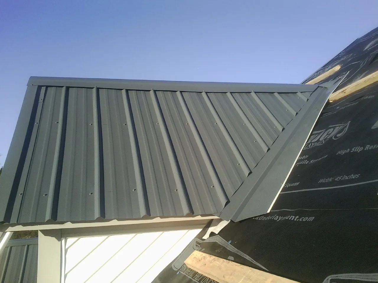 Gray metal roof panels going on over a garage gable in Gilbert